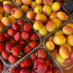 Top view of juicy strawberries and ripe peaches displayed at a local market, perfect for healthy eating.