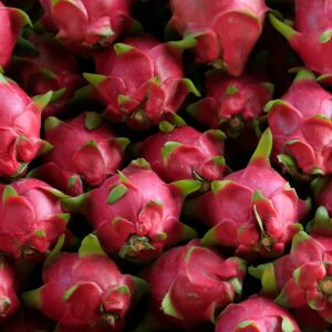 Close-up of vibrant pink dragon fruits stacked together, showcasing their unique texture and freshness.